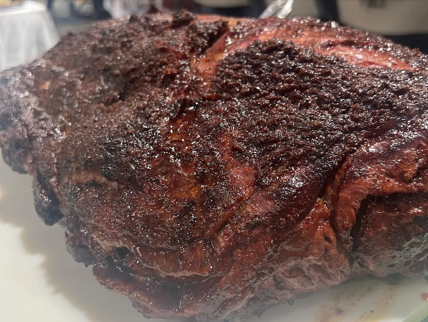 An extreme close-up of a dark, heavily crusted piece of smoked beef, showing the peppery bark in detail.